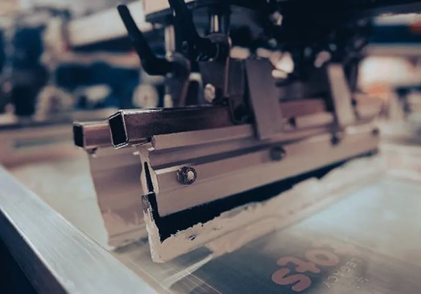 A squeegee and screen on an Ad It Up screen printing press